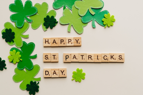 Scrabble letter tiles spelling out Happy St. Patrick's Day surrounded by felt shamrocks