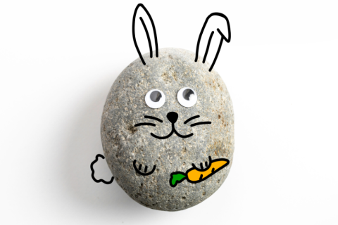 small grey rock decorated to look like a bunny holding a carrot