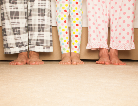 two sets of adult feet and legs and one set of child's feet and legs, all wearing patterned pajamas