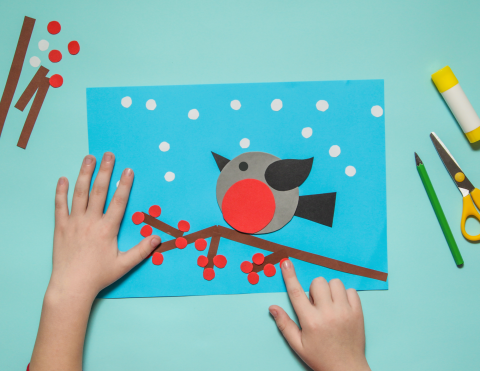 Child creating a winter bird craft from colored paper