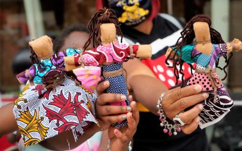 hands holding abayomi dolls (rag dolls made with brightly colored African cloth)