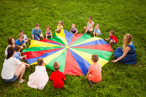 children and adult caregivers playing with a parachute 