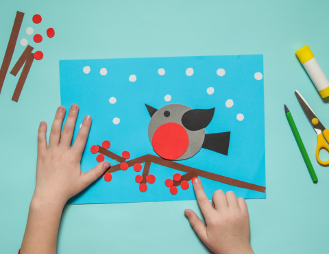 child's hands making a bird from paper
