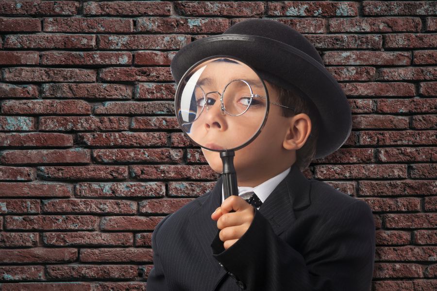 kid in a suit and bowler cap holding a spy glass