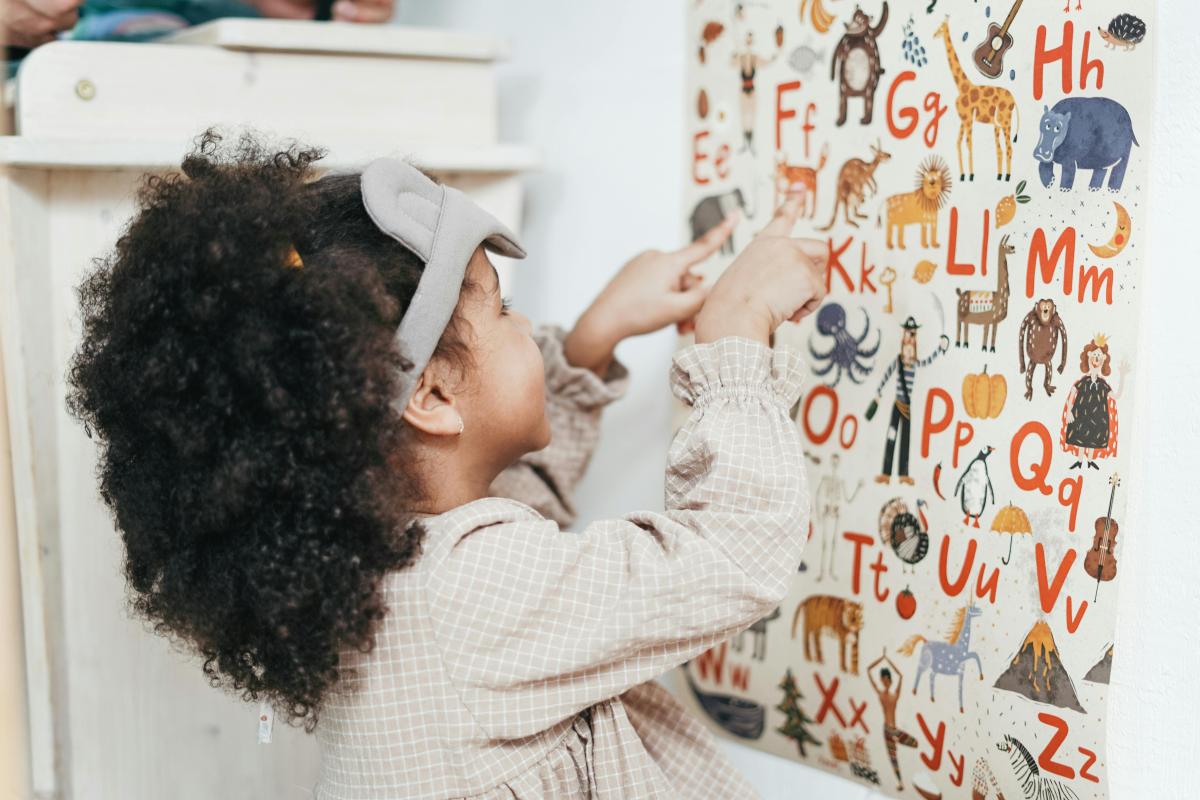 child looking at a poster with the letters of the alphabet